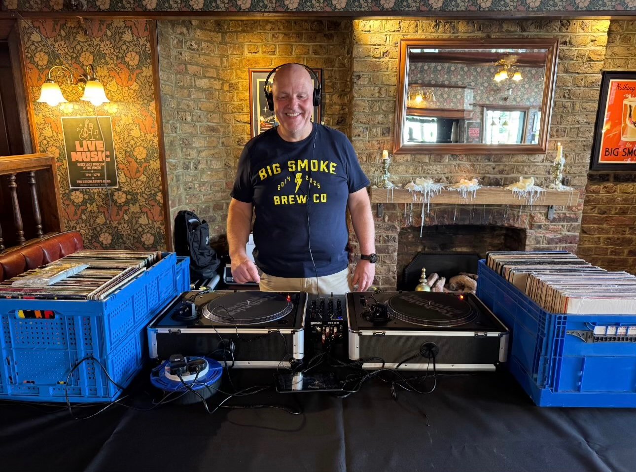 DJ Curly smiling behind twin Technics decks with crates of vinyl